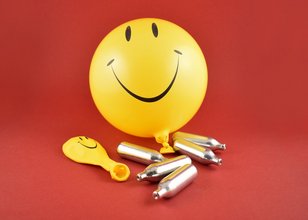 Luftballons mit Smiley-Motiv, daneben Lachgaskapseln