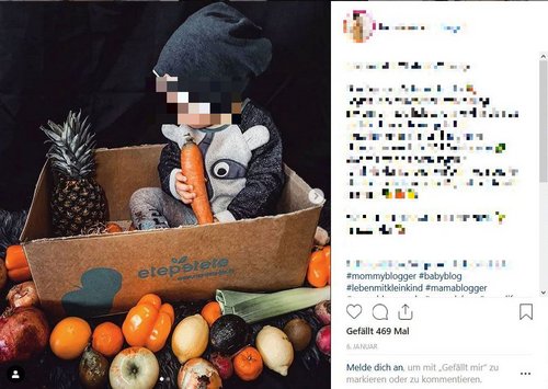 Ein Kleinkind sitzt in einer Kiste mit Obst. Um die Kiste herum sind ebenfalls diverse Früchte- und Gemüsesorten drapiert.